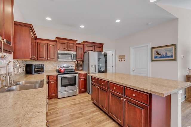 kitchen with sink, light hardwood / wood-style flooring, appliances with stainless steel finishes, a kitchen island, and decorative backsplash