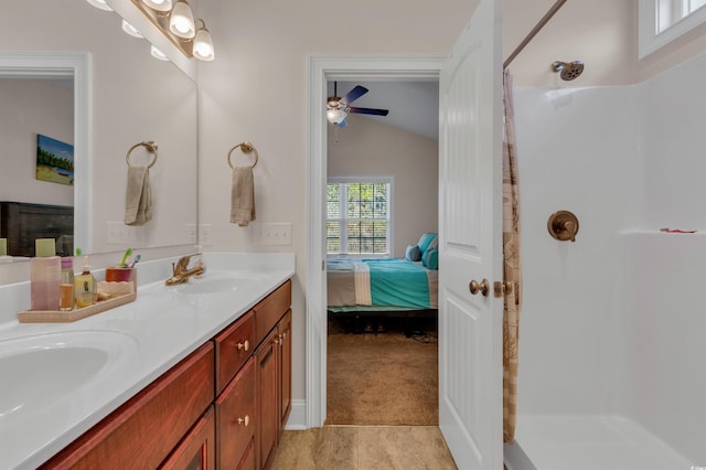 bathroom featuring vanity, vaulted ceiling, and a shower