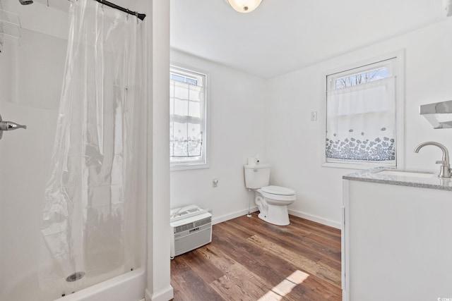 bathroom featuring wood-type flooring, curtained shower, vanity, a wall unit AC, and toilet