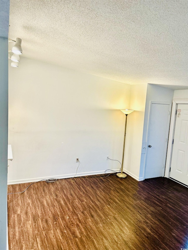 empty room with dark hardwood / wood-style floors and a textured ceiling