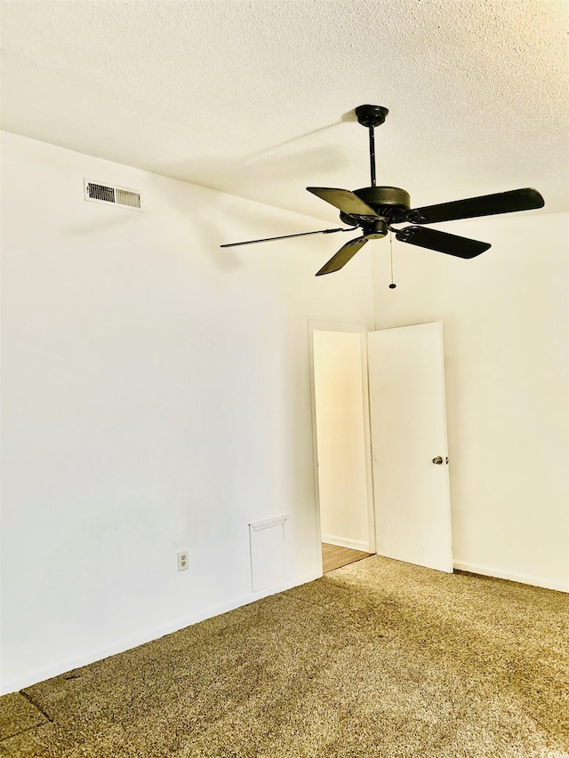 carpeted empty room featuring ceiling fan and a textured ceiling