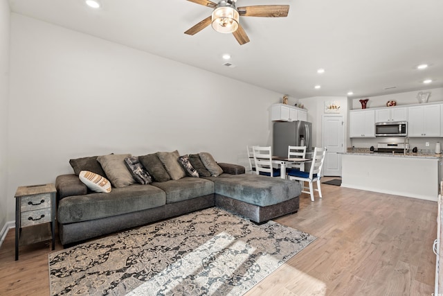 living room featuring light hardwood / wood-style flooring and ceiling fan