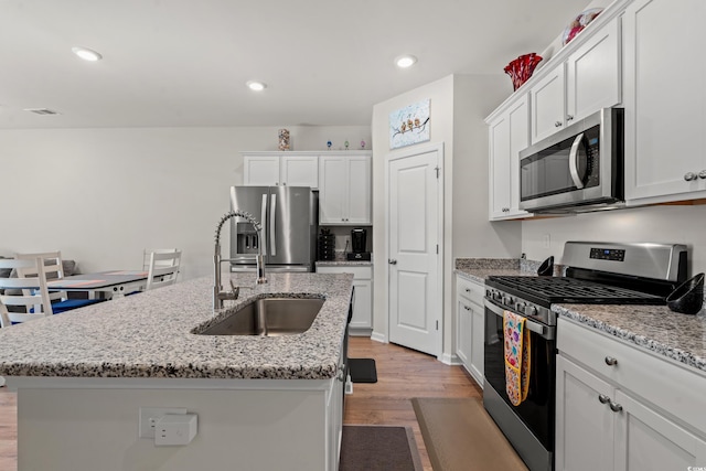 kitchen with white cabinetry, appliances with stainless steel finishes, and a center island with sink