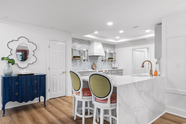 kitchen featuring custom range hood, white cabinets, a sink, and a peninsula