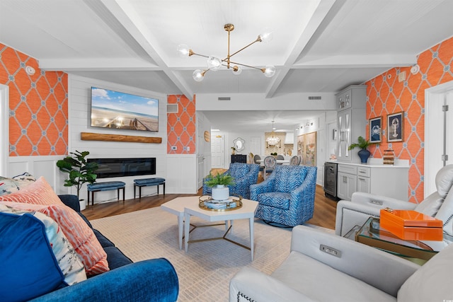 living area with a glass covered fireplace, a chandelier, light wood-type flooring, coffered ceiling, and wallpapered walls