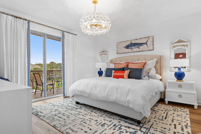 bedroom with a chandelier, access to outside, and wood finished floors