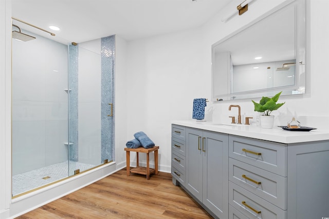 bathroom with a walk in shower, wood finished floors, vanity, and baseboards