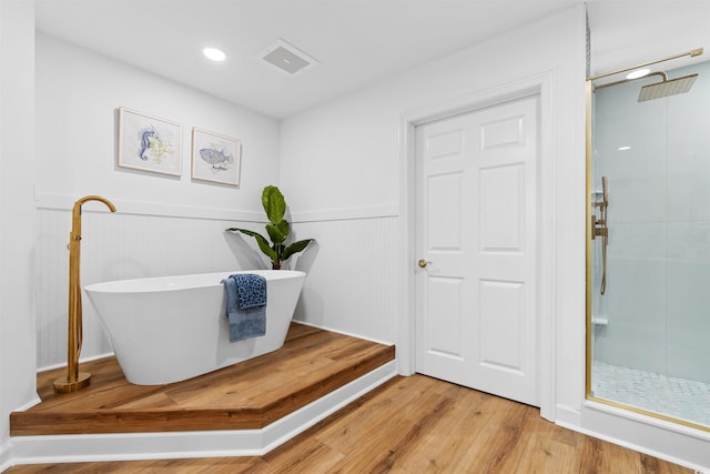 bathroom featuring a freestanding tub, a wainscoted wall, wood finished floors, visible vents, and walk in shower