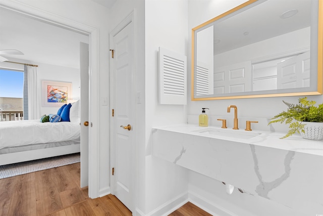 bathroom featuring baseboards, a sink, ensuite bathroom, and wood finished floors