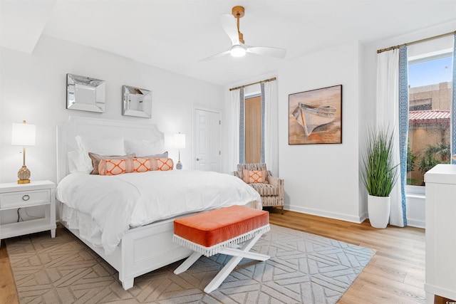 bedroom featuring a ceiling fan, baseboards, and light wood finished floors