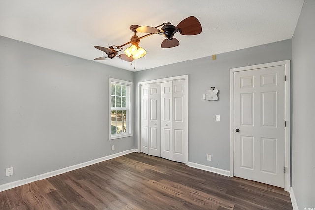 unfurnished bedroom with ceiling fan, dark hardwood / wood-style flooring, and a closet