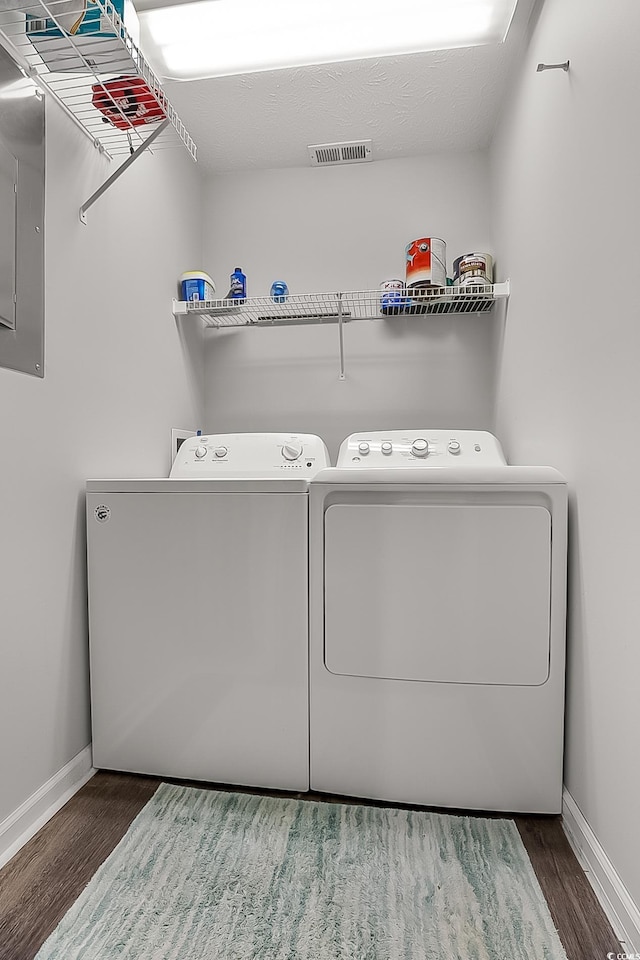 laundry area with dark wood-type flooring, electric panel, and washer and clothes dryer