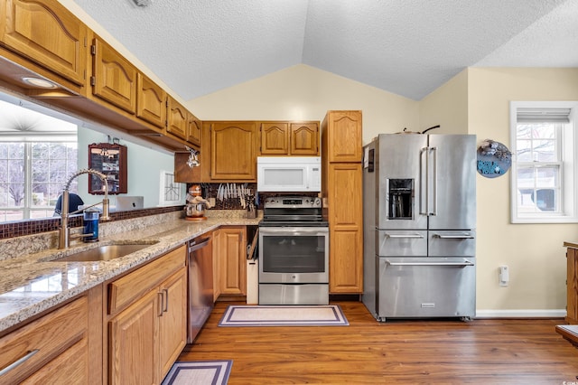 6716 Wisteria Dr, Myrtle Beach, SC 29588 - kitchen with lofted ceiling, light stone counters, stainless steel appliances, wood finished floors, and a sink