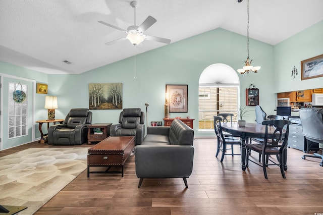 living area with visible vents, wood finished floors, a textured ceiling, high vaulted ceiling, and ceiling fan with notable chandelier