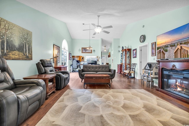 living room with a ceiling fan, a glass covered fireplace, high vaulted ceiling, and wood finished floors