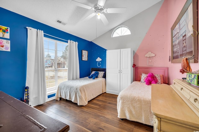 bedroom featuring dark wood-style flooring, visible vents, a ceiling fan, vaulted ceiling, and a textured ceiling