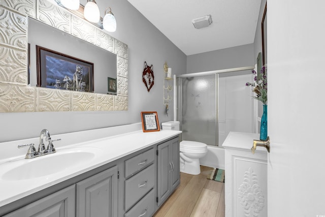 full bathroom featuring toilet, enclosed tub / shower combo, wood finished floors, and vanity