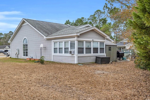 back of property featuring a shingled roof and cooling unit