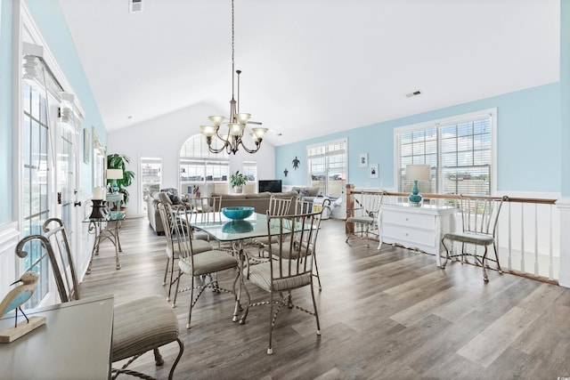 dining area with high vaulted ceiling, wood finished floors, visible vents, and an inviting chandelier