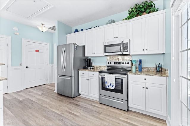 kitchen with light stone counters, visible vents, appliances with stainless steel finishes, light wood-style floors, and white cabinets