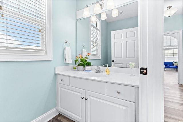 bathroom with wood finished floors, vanity, and baseboards