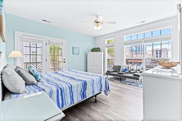 bedroom with access to outside, multiple windows, wood finished floors, and visible vents