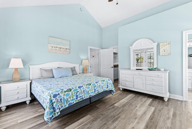 bedroom with a closet, ceiling fan, wood finished floors, high vaulted ceiling, and baseboards