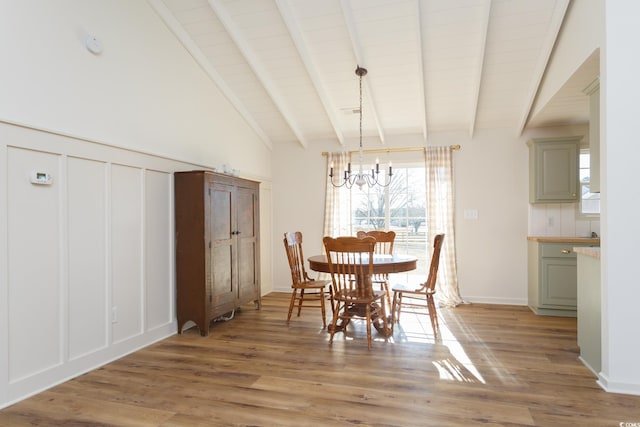 dining room featuring a chandelier, lofted ceiling with beams, and light wood-type flooring