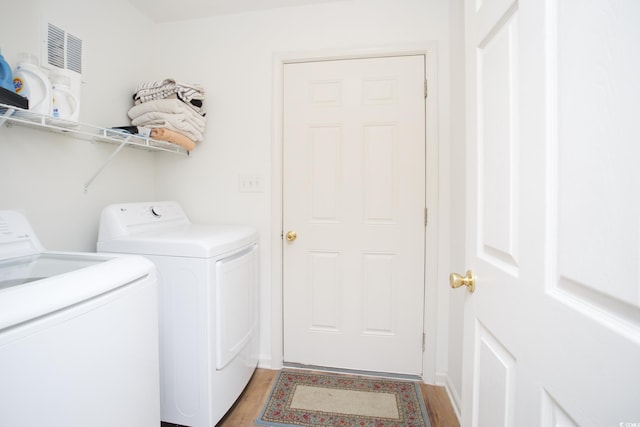 laundry area with wood-type flooring and washer and clothes dryer