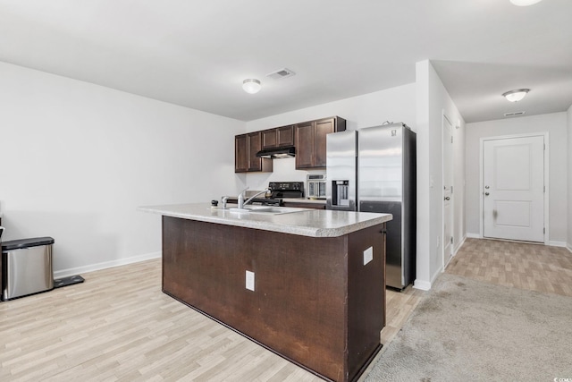 kitchen featuring sink, stainless steel fridge, dark brown cabinetry, a center island with sink, and light hardwood / wood-style flooring