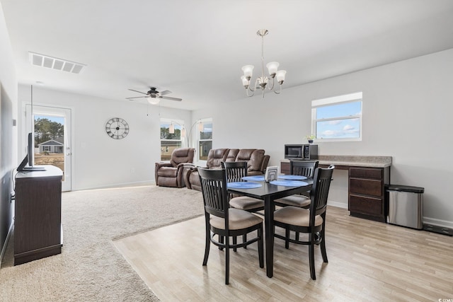 dining room featuring a healthy amount of sunlight, ceiling fan with notable chandelier, and light wood-type flooring