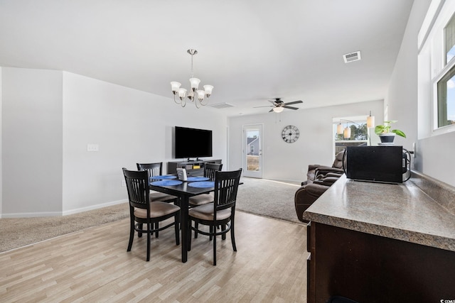 dining space with plenty of natural light, ceiling fan with notable chandelier, and light wood-type flooring