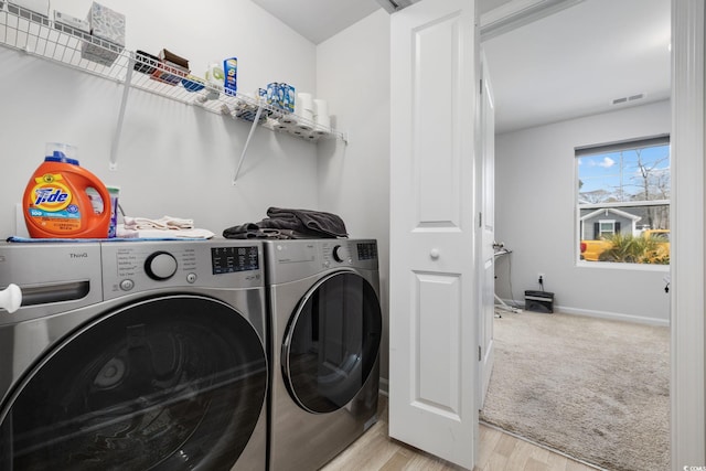 laundry room with washer and clothes dryer and light wood-type flooring