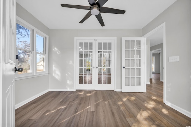 empty room featuring ceiling fan, french doors, wood finished floors, and baseboards