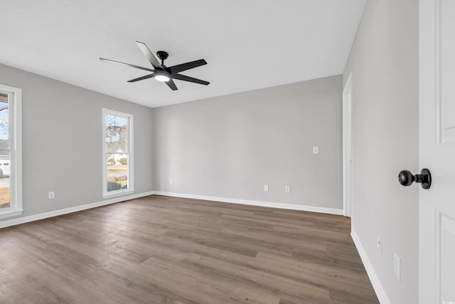 unfurnished room featuring dark wood-style flooring, a ceiling fan, and baseboards