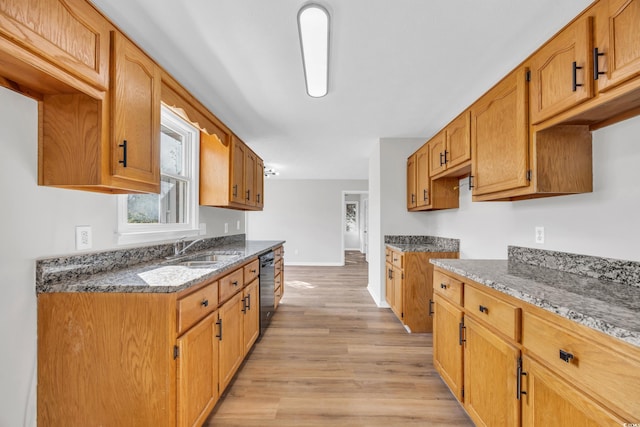 kitchen featuring dark stone counters, a sink, light wood-type flooring, dishwasher, and baseboards