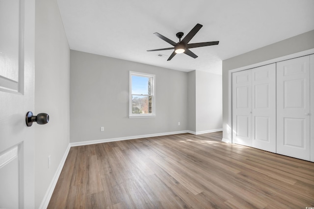 unfurnished bedroom with ceiling fan, a closet, baseboards, and wood finished floors