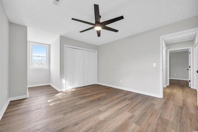 unfurnished bedroom featuring visible vents, a closet, baseboards, and wood finished floors