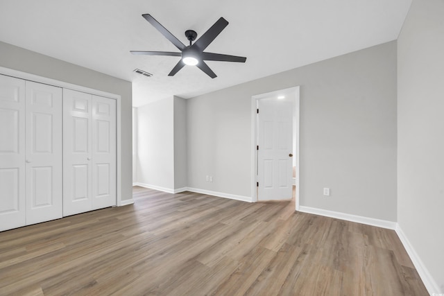 unfurnished bedroom with a closet, visible vents, baseboards, and wood finished floors