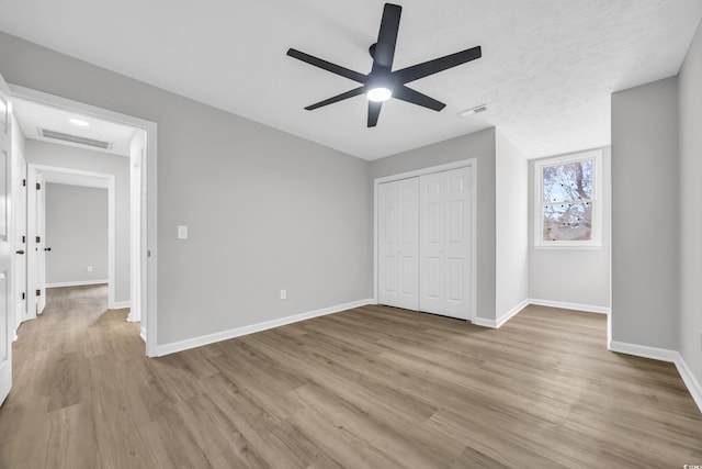 unfurnished bedroom featuring visible vents, a closet, baseboards, and wood finished floors