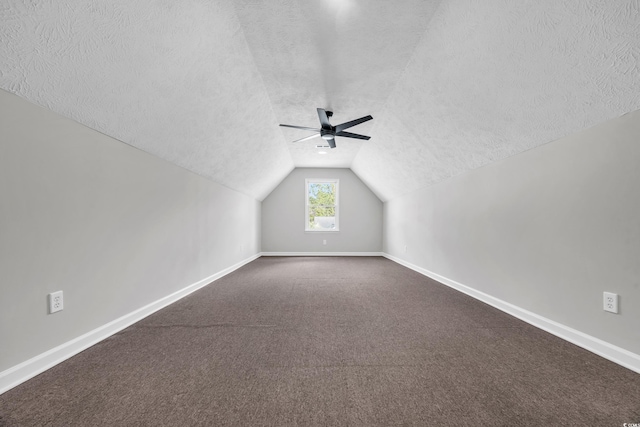 bonus room featuring dark carpet, vaulted ceiling, a textured ceiling, and baseboards