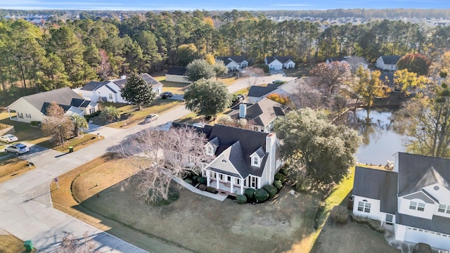 drone / aerial view with a forest view, a water view, and a residential view