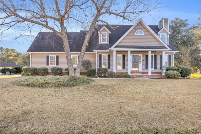 new england style home with a shingled roof, a chimney, and a front lawn