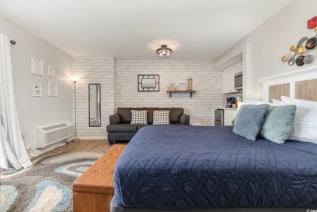 bedroom featuring brick wall, a wall unit AC, and light hardwood / wood-style flooring