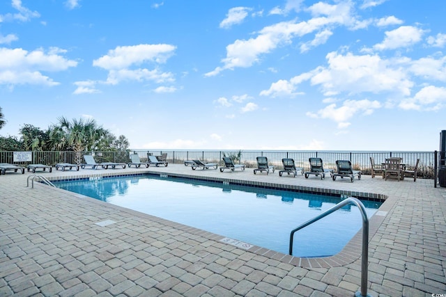 view of pool featuring a patio and a water view