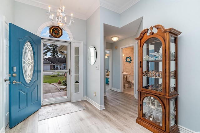 foyer entrance with crown molding, light hardwood / wood-style flooring, and a notable chandelier