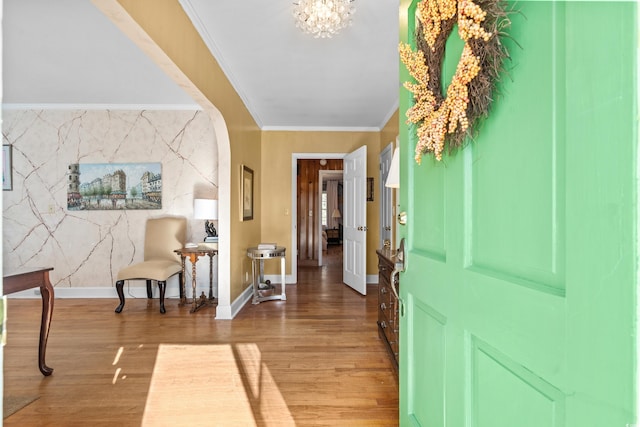 entrance foyer with ornamental molding, hardwood / wood-style floors, and a chandelier