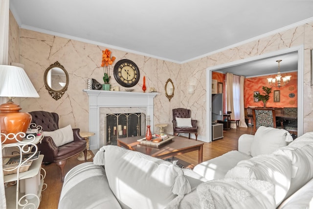 living room with hardwood / wood-style flooring, ornamental molding, a notable chandelier, and a high end fireplace