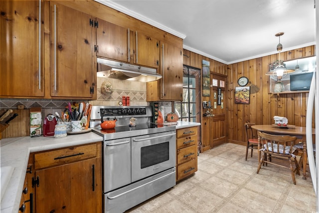 kitchen featuring crown molding, hanging light fixtures, wooden walls, tasteful backsplash, and range with two ovens