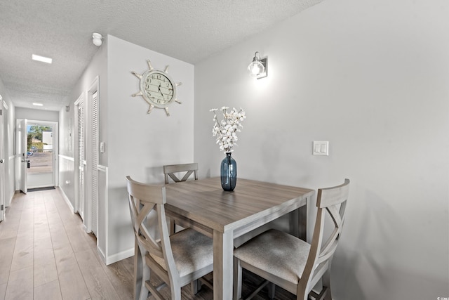 dining area featuring light hardwood / wood-style floors and a textured ceiling